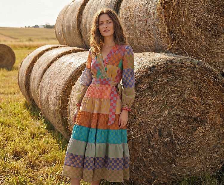 “Woman wearing multicolor patchwork midi dress standing by hay bales in countryside field”
